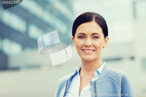 Image of young smiling businesswoman over office building