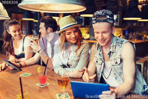 Image of happy friends with tablet pc and drinks at bar