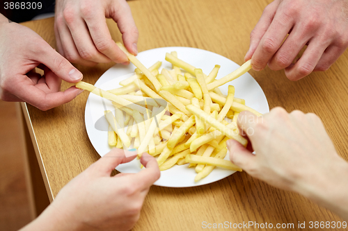 Image of close up of hands taking french fries from plate