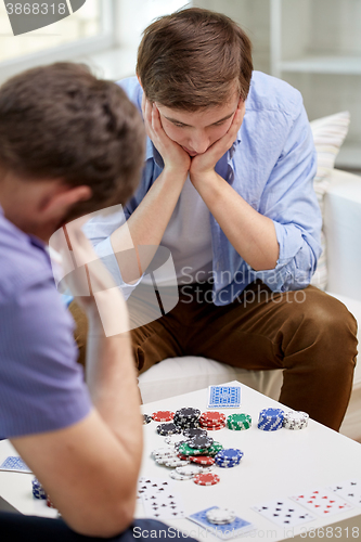 Image of close up of male friends playing cards at home