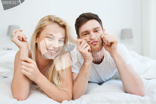 Image of happy couple lying in bed at home