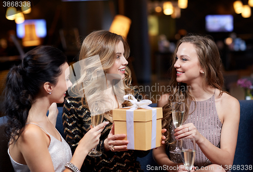 Image of happy women with champagne and gift at night club