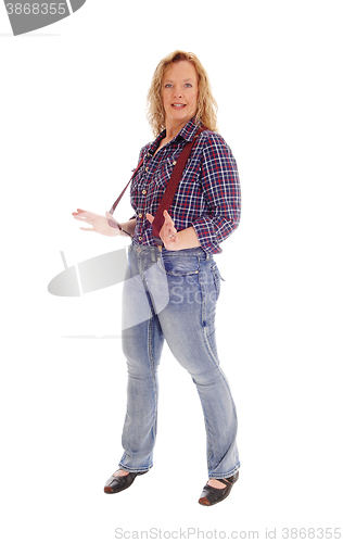 Image of A blond woman standing in jeans and suspender.