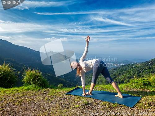 Image of Woman doing Ashtanga Vinyasa yoga asana Parivrtta trikonasana