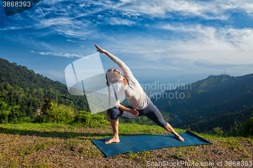 Image of Woman practices yoga asana Utthita Parsvakonasana outdoors