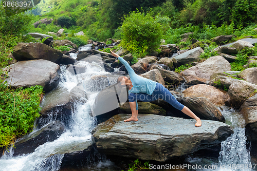 Image of Woman practices yoga asana Utthita Parsvakonasana outdoors