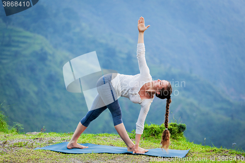 Image of Woman doing Ashtanga Vinyasa yoga asana Parivrtta trikonasana