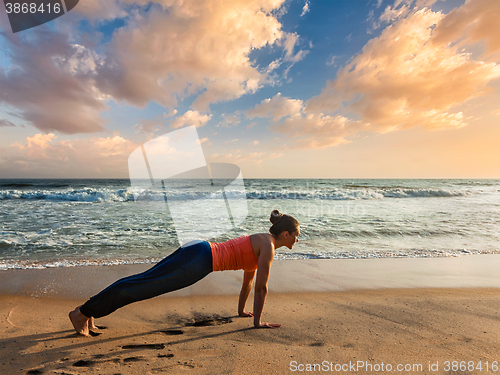 Image of Woman doing Hatha yoga asana plank pose outdoors