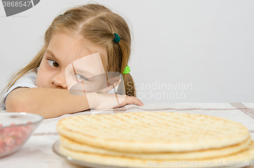 Image of The girl at the kitchen table laid her head on his hand, and with an appetite for looking at cakes in front of her