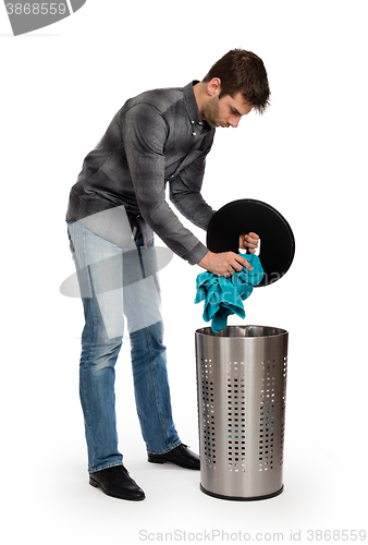 Image of Young man putting a dirty towel in a laundry basket