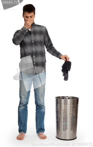 Image of Young man putting dirty socks in a laundry basket