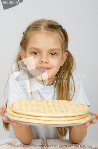 Image of The girl with a slight smile holding a pizza crust on a plate