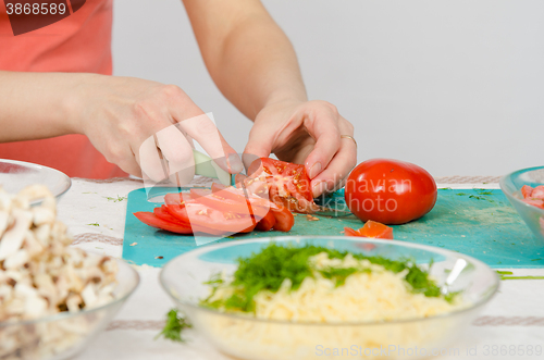Image of Close-up of female hands cutting tomato on kitchen table
