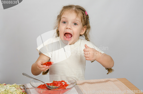 Image of Little girl with mouth open holding a large slice of tomato
