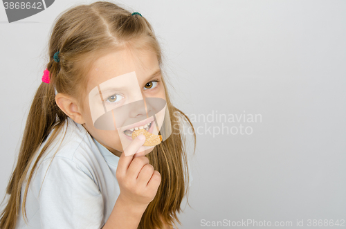 Image of Portrait of a little six year old girl biting a cookie