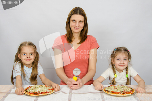 Image of At the table sat my mother with a knife for pizza and two daughters to whom two pizzas