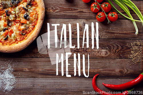Image of Italian pizza with tomatoes on a wooden table, top view, close-up