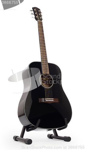 Image of Black acoustic guitar on stand, isolated