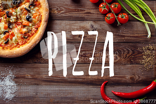 Image of Italian pizza with tomatoes on a wooden table, top view, close-up. 