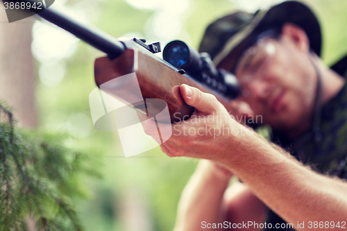 Image of soldier or hunter shooting with gun in forest