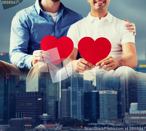 Image of close up of happy gay male couple with red hearts