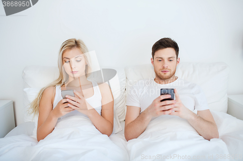 Image of couple with smartphones in bed