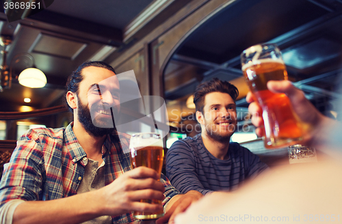 Image of happy male friends drinking beer at bar or pub