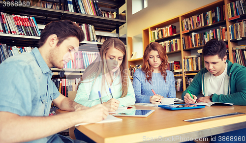 Image of happy students writing to notebooks in library