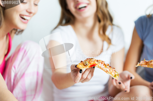 Image of happy friends or teen girls eating pizza at home