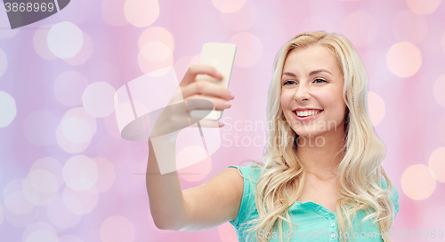 Image of smiling young woman taking selfie with smartphone