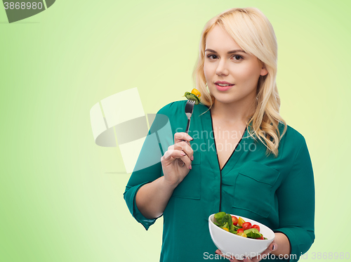 Image of smiling young woman eating vegetable salad
