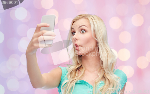 Image of funny young woman taking selfie with smartphone