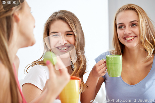 Image of happy young women drinking tea with sweets at home