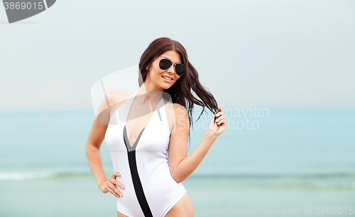 Image of smiling young woman with sunglasses on beach