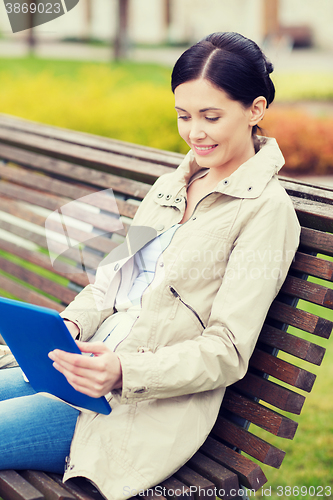 Image of woman with tablet pc sitting on bench in park