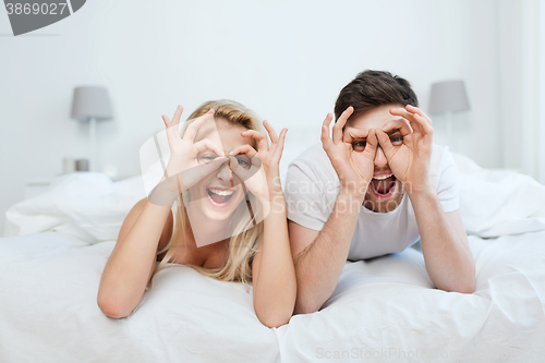 Image of happy couple lying in bed at home