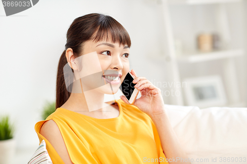 Image of happy asian woman calling on smartphone at home