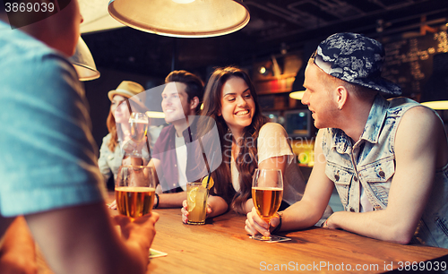 Image of happy friends with drinks talking at bar or pub