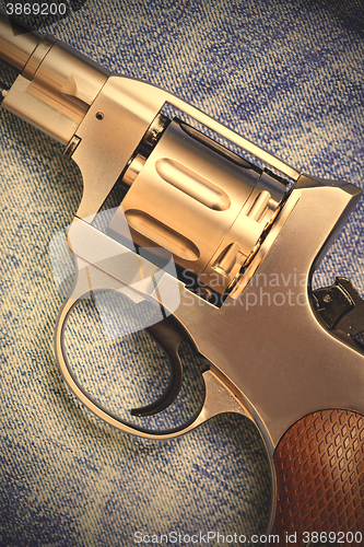 Image of old revolver on blue jeans