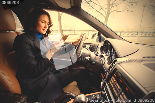 Image of woman with a smartphone in hand in interior of car