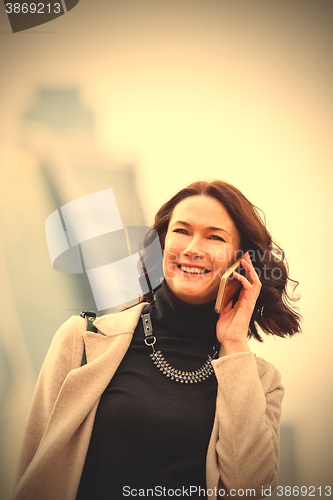 Image of business woman in a bright coat talking on a cell phone