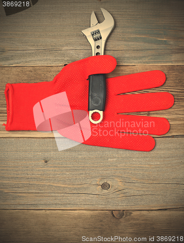 Image of red glove and a pipe wrench