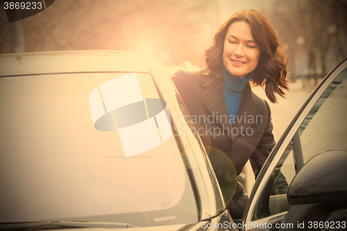 Image of smiling middle-aged woman sits in the car 