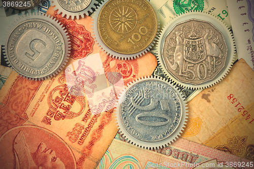 Image of coin gear on the background of banknotes