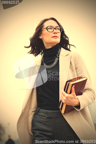 Image of dark-haired middle-aged woman with books