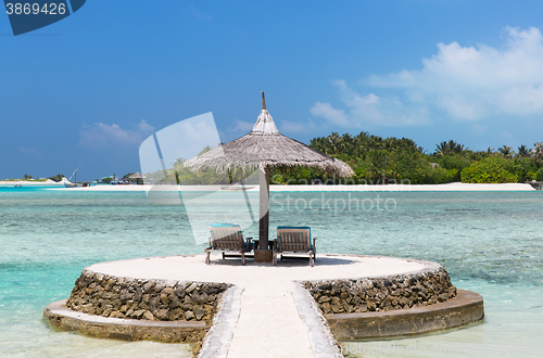 Image of palapa and sunbeds by sea on maldives beach