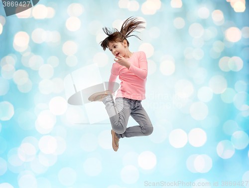 Image of happy little girl jumping in air over blue lights