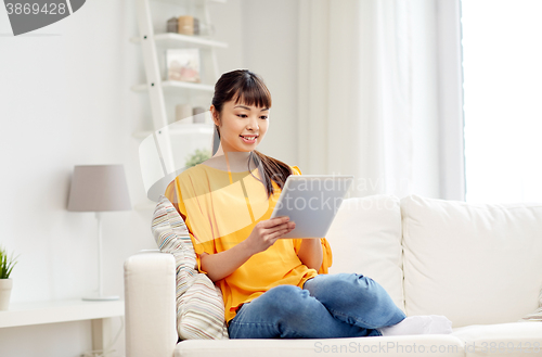 Image of happy young asian woman with tablet pc at home