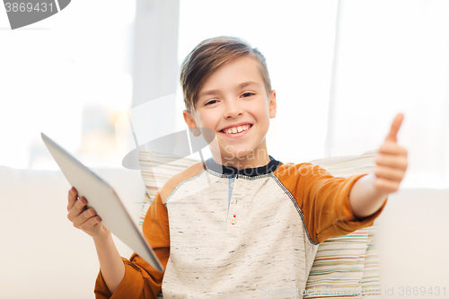 Image of smiling boy with tablet showing thumbs up at home