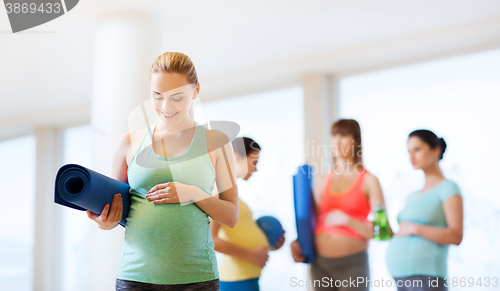 Image of happy pregnant woman with mat in gym